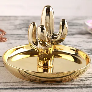Golden cactus ceramic jewelry tray for rings and necklaces on vintage wood background