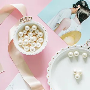 Detail of elegant white ceramic jewelry tray with gold crown and loose cream pearls