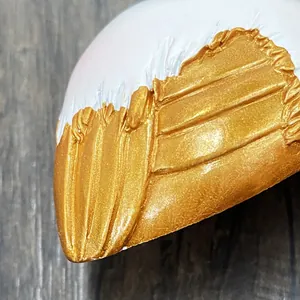 Detailed macro shot of flamingo ornament with smooth white resin and carved golden feathers