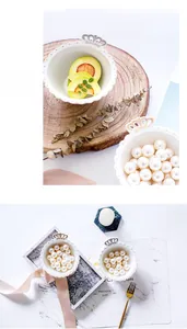 Macro detail of white ceramic jewelry dish featuring gold crown handle and wavy edges