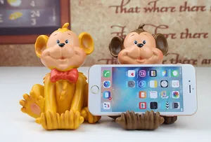 Detail of two resin monkey phone holders in yellow and brown holding a smartphone