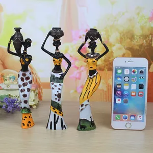 Three African tribal woman resin figurines set with ethnic patterns and jars on wooden table