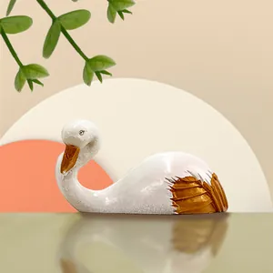 Detail of elegant white swan figurine with gold feather accents on a minimalist background