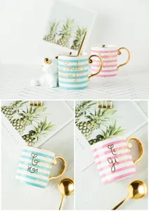 Detail of pink and blue ceramic mugs with gold lettering and metallic spoons