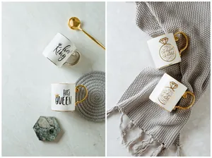 Close-up of ceramic mugs with gold rims and HIS QUEEN or HER KING decorative text