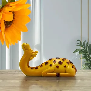 Detailed view of yellow giraffe resin ornament on wooden desk with floral accents