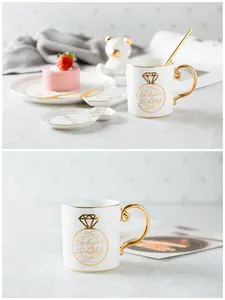 Detail of white ceramic mug set with gold handle and to have and to hold diamond design