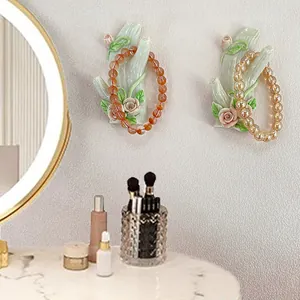 Ceramic hand-shaped wall jewelry hooks with pink rose relief holding bead bracelets