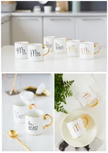 Close-up of Mr and Mrs gold-rimmed ceramic mugs with elegant scrolls and gold handles