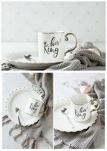 Detail of white ceramic mug with her King script, golden crown and scalloped saucer