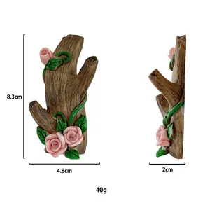 Macro detail of a resin tree branch wall hook featuring pink roses and green vines