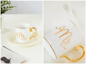 Close-up of elegant ceramic mug with gold handle and Mr inscription on a white surface