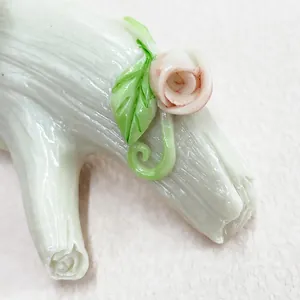 Macro detail of resin tree branch hook with delicate pink roses and green leaf textures