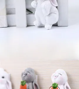 Detail showing cartoon rabbit resin adhesive wall hooks with carrot decor on white fence
