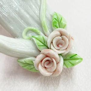 Detail of hand-carved floral wall hook featuring realistic light pink roses and green leaves