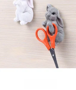 Adhesive resin wall hook in cute rabbit shape holding orange scissors on beige wall