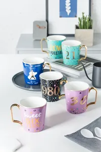 Vista dall'alto di tazze in ceramica di lusso con manici dorati e design colorati