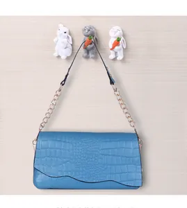 Detail of blue crocodile pattern shoulder bag hanging on three cartoon rabbit hooks