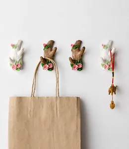 Rustikale Wandhaken in Astform mit Harzrosen, die eine Tasche und Deko-Elefanten halten