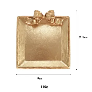 Détail du plateau à bijoux doré avec nœud, montrant les dimensions 9,5 cm et 110 g
