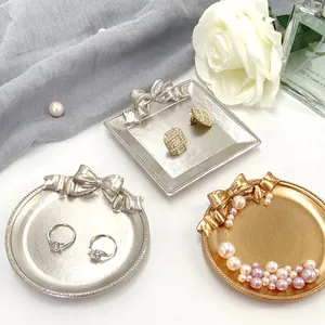 Vue détaillée des plateaux à bijoux avec nœuds en finitions argent et or vintage