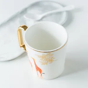 Dettaglio della tazza in ceramica con giraffa, manico dorato e piattino in marmo