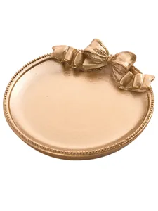 Macro d'un plateau à bijoux rond doré mat avec noeud élégant et bordure perlée