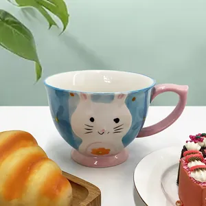 Detailed view of hand-painted cat ceramic mug featuring pink handle and floral patterns
