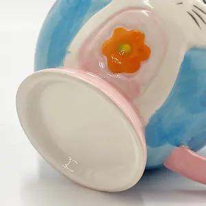Detail of the glazed ceramic mug base featuring hand-painted floral patterns in light blue