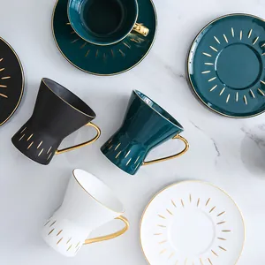 Ceramic coffee cup and saucer set with gold trim in emerald, black, and white colors