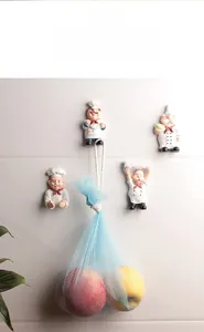 Cartoon chef sticky wall hook holding a mesh bag on white marble kitchen tiles