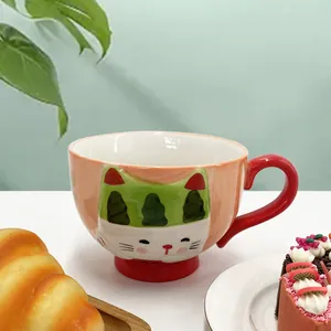 Close-up of cute hand-painted ceramic cat mug with a vibrant red handle and base