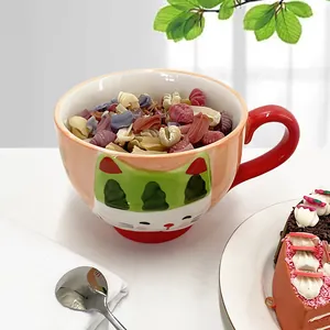 Top view of a ceramic cat-themed bowl with red handle filled with colorful pasta