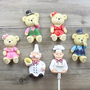 Macro view of cute resin chef and teddy bear power plug holders for cable organization