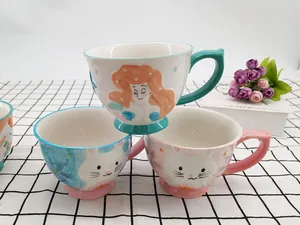 Detail view of colorful ceramic mugs with embossed mermaid and cat motifs