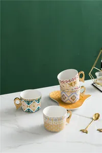 Détail de tasses en céramique bohème avec anses ailes d'ange dorées sur marbre