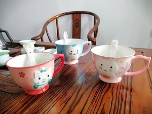 Detail view of 3D embossed ceramic mugs with cartoon cat and rabbit motifs and spoons