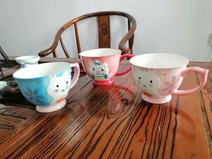 Detail of 3D embossed cartoon cat and rabbit patterns on colorful ceramic breakfast mugs