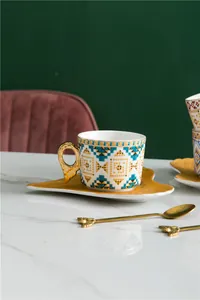 Détail d'une tasse à café en céramique bohème avec anse aile dorée et motifs géométriques