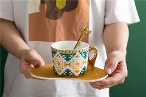 Détail d'une tasse à café vintage à motifs géométriques avec cuillère ange tenue à la main