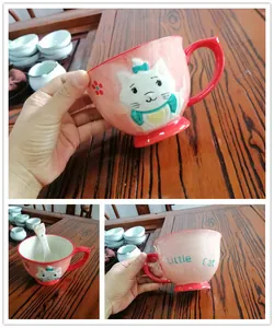 Detailed view of a pink ceramic mug with a 3D cat relief and a matching ceramic spoon
