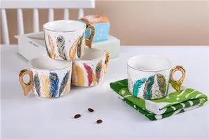 Gros plan d'une tasse en céramique avec anse aile dorée et motifs plumes colorées