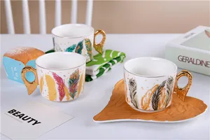 Détail d'une tasse en céramique avec anse aile d'ange dorée et motif de plumes