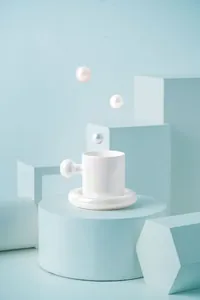 Macro detail of iridescent pearl ceramic coffee cup with large ball handle and ring saucer