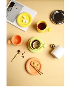 Close-up of ceramic coffee mug set with spherical handle and colorful donut plates