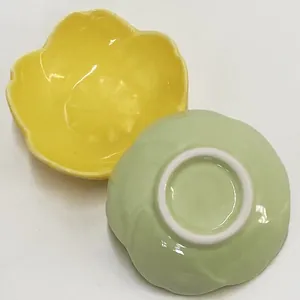 Close-up of ceramic petal-shaped sauce dishes in yellow and green with smooth glaze