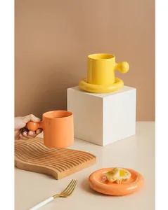 Close-up of modern ceramic coffee mug with large ball handle and thick donut saucer set