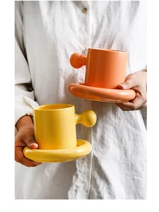Detailed close-up of a creative ceramic coffee mug with a round handle and thick saucer
