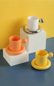 Close-up of modern ceramic mugs and saucers with round handles in yellow and blue setting