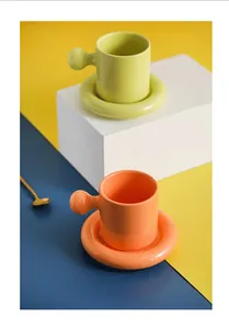 Detail of vibrant ceramic coffee cups with chubby handles on matching thick saucer trays